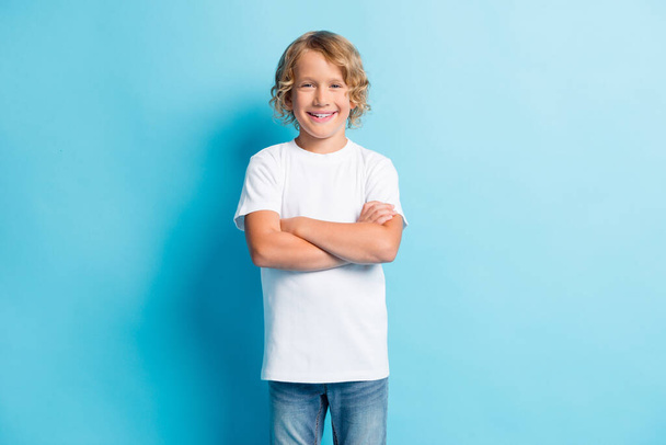 Photo of small child folded arms curly hairstyle look camera wear white shirt isolated blue color background - Фото, зображення