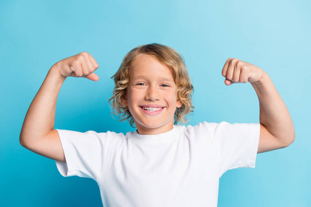 Photo of confident boy show his muscles wear casual style clothes isolated over blue color background - Photo, Image