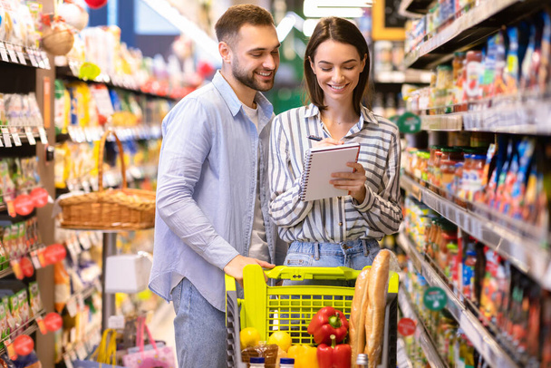 Young couple with shopping list in supermarket - Photo, Image