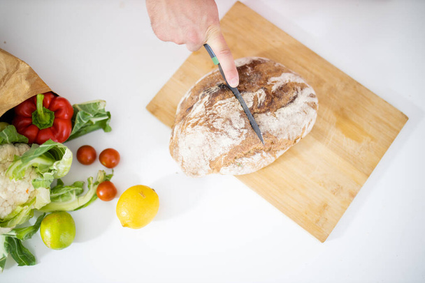 Mani maschili affettare il pane su un tagliere - Foto, immagini