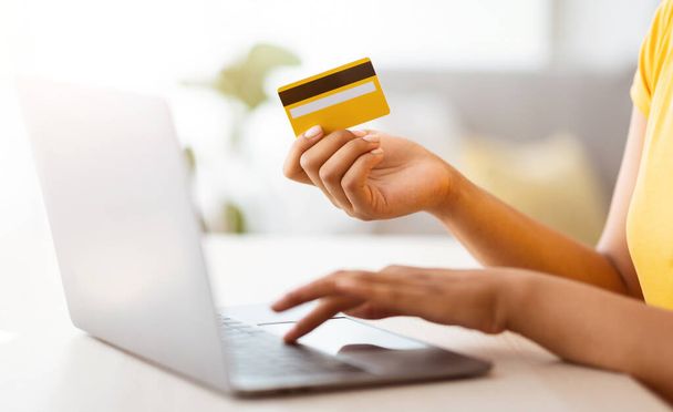 Черная женщина использует ноутбук и кредитную карту дома - Фото, изображение