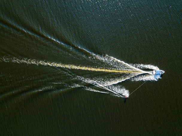 Vista aérea de drones. Acorde surfando atrás de um barco no rio em um dia ensolarado de verão. - Foto, Imagem
