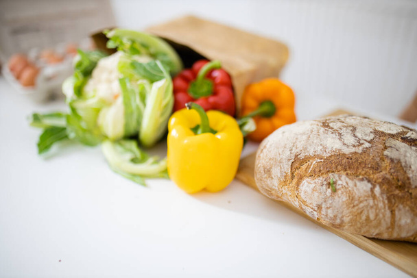 Harangpaprika és karfiol a fehér asztalon a kenyér mellett - Fotó, kép