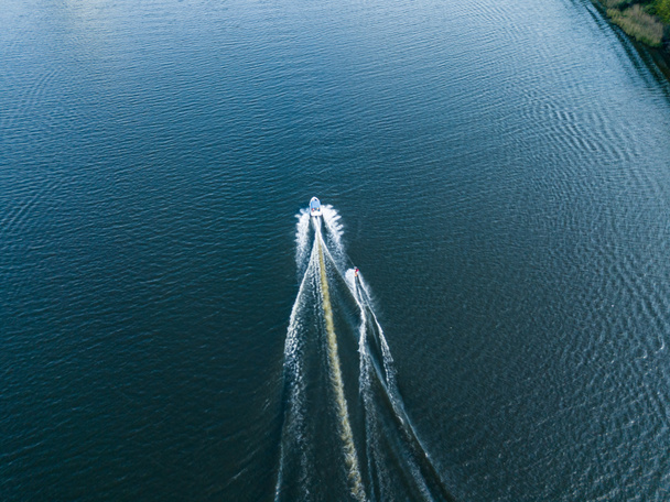 Vista aérea del dron. Despierta surfeando detrás de un barco en el río en un soleado día de verano. - Foto, Imagen