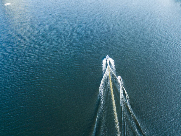 Widok z lotu ptaka. Obudzić surfing za łodzią na rzece w słoneczny letni dzień. - Zdjęcie, obraz