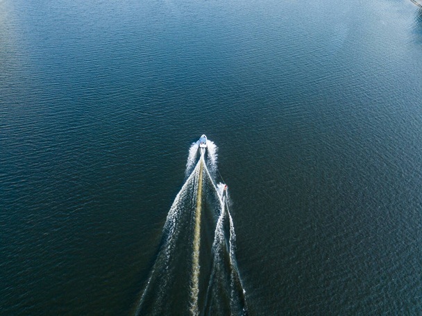 Vista aérea del dron. Despierta surfeando detrás de un barco en el río en un soleado día de verano. - Foto, imagen