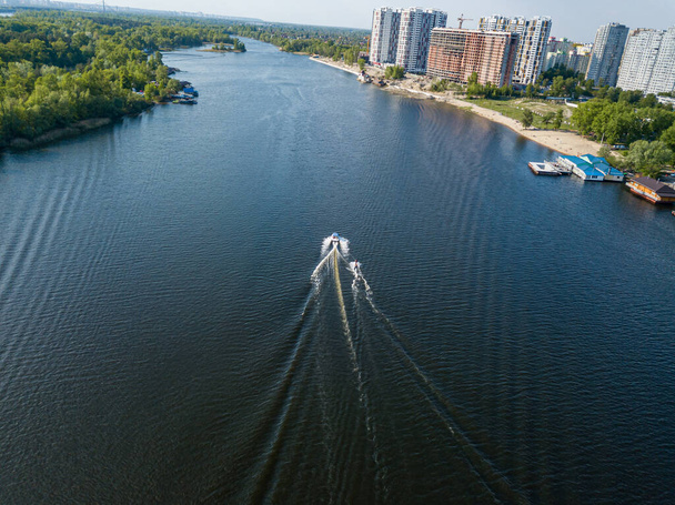 Veduta aerea del drone. Svegliati facendo surf dietro una barca sul fiume in una giornata estiva soleggiata. - Foto, immagini