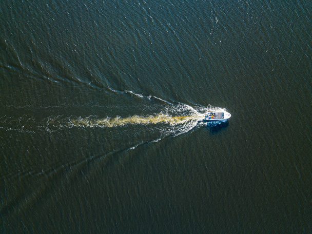 Вид на повітряний безпілотник. Моторний човен пливе вздовж річки. Сонячний літній день, маленькі хвилі
. - Фото, зображення