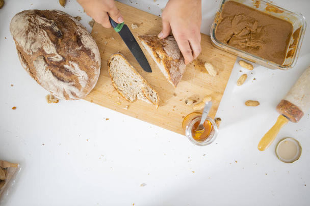 Női kéz kenyeret szeletel egy vágódeszkán - Fotó, kép