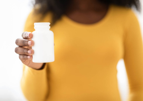 Gros plan de femme enceinte noire tenant un pot blanc avec des médicaments - Photo, image