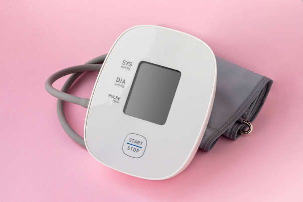 Automatyczny monitor ciśnienia krwi na różowym tle. Tonometr elektroniczny medyczny - Zdjęcie, obraz