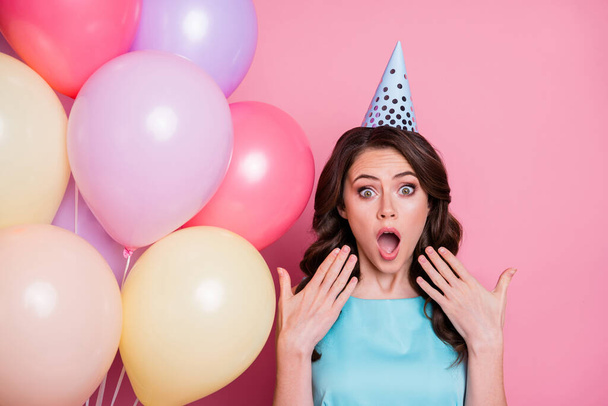 Photo of curly charming shocked lady festive event birthday party many air balloons friends arrange surprise holiday wear blue teal dress cone hat isolated pastel pink color background - Fotoğraf, Görsel