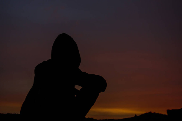 un ragazzo con una felpa seduta a terra la sera - Foto, immagini