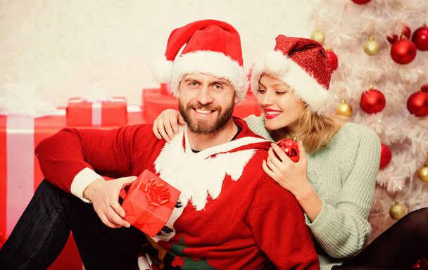 Couple in love enjoy christmas holiday celebration. Loving couple cuddle smiling while unpacking gifts with christmas tree background. Family prepared christmas gifts. Christmas is time for giving - Φωτογραφία, εικόνα