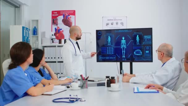 Lääkäri esittää ihmisen sisäisen rakenteen kollegoille digitaalisen näytön avulla - Materiaali, video