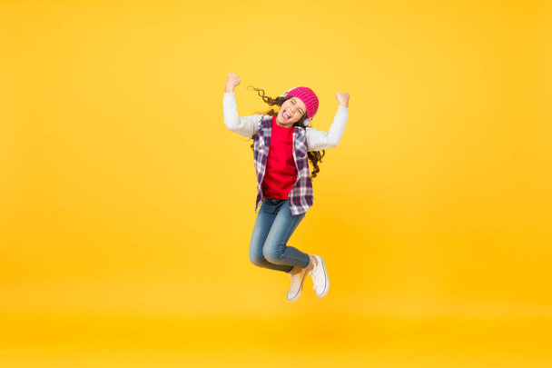 Happy active kid enjoy listening and jumping to music playing in headphones yellow background, pleasure - Foto, Bild