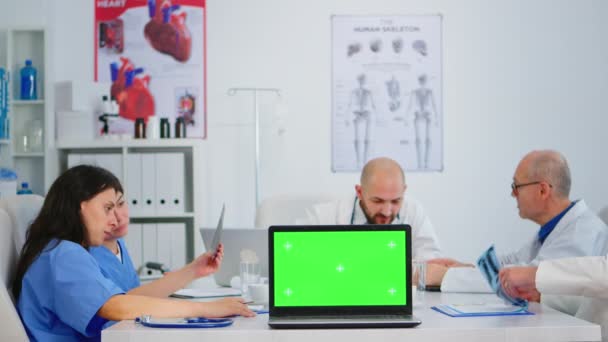 Lékařští kolegové pracující v nemocniční kanceláři pomocí notebooku s maketovým displejem - Záběry, video