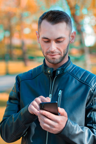 Handsome Guy Using Smartphone at Autumn Park - Valokuva, kuva