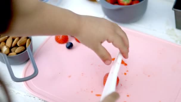 Mani femminili che tagliano fragole su un tagliere rosa - Filmati, video