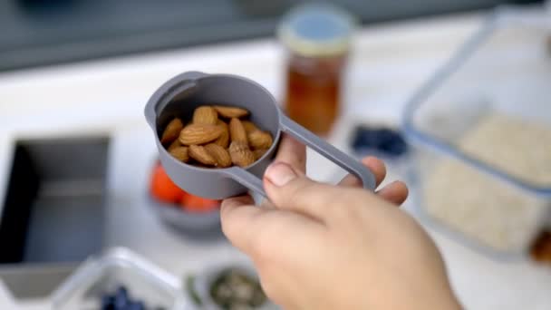 Measuring cup full of fresh almonds above ingredients in plastic containers - Footage, Video