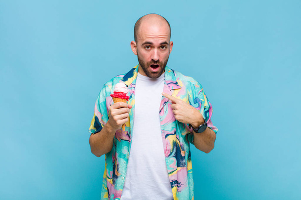 young bald man looking shocked and surprised with mouth wide open, pointing to self - Foto, imagen