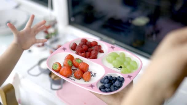 Γυναικεία χέρια μαζεύουν φράουλες από ένα ροζ δίσκο με μούρα - Πλάνα, βίντεο
