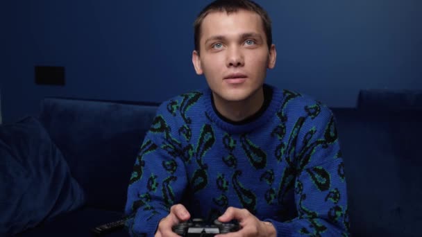 Μπροστά όψη ενός ενθουσιασμένου Καυκάσου που παίζει βιντεοπαιχνίδια και χρησιμοποιεί χειριστήριο χειριστηρίου. Ευτυχισμένος άνθρωπος που παίζει παιχνίδια στον καναπέ στο σπίτι. - Πλάνα, βίντεο