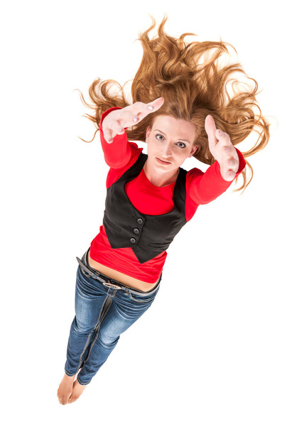 Υψηλή γωνία πλήρες μήκος μιας νεαρής γυναίκας που βρίσκεται στο λευκό με απλωμένα ξανθά μαλλιά και τα χέρια τεντωμένα στην κάμερα χαμογελώντας χαρούμενα στην κάμερα. - Φωτογραφία, εικόνα