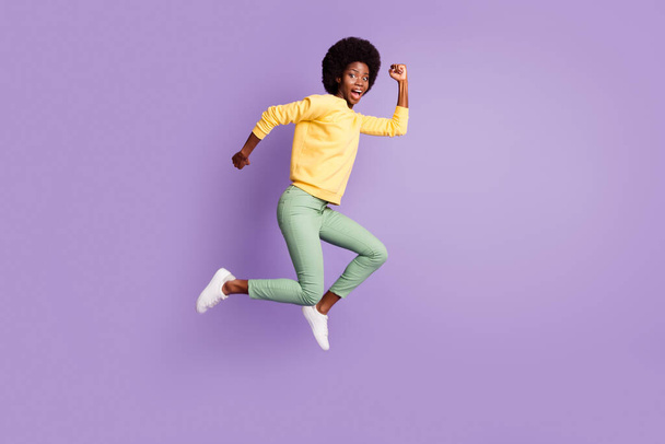 Full length profile side photo of crazy afro american girl jump run copyspace isolated over purple color background - Zdjęcie, obraz