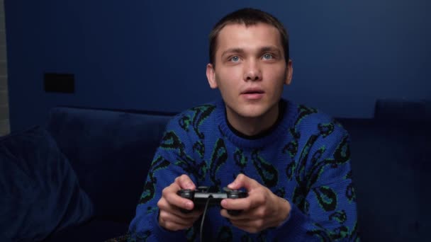 Egy izgatott kaukázusi férfi, aki videojátékozik és joystick vezérlőt használ. Boldog ember játszik kanapén otthon. - Felvétel, videó