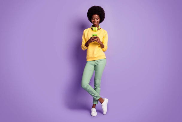 Full size photo of afro american girl chat on cellphone wear green pants yellow jumper isolated over purple color background - Fotó, kép