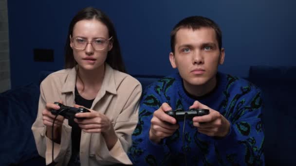 Jeunes gens heureux jouant à des jeux vidéo sur la console tout en étant assis sur le canapé devant la télévision. Couple millénaire passer du bon temps ensemble à la maison. - Séquence, vidéo