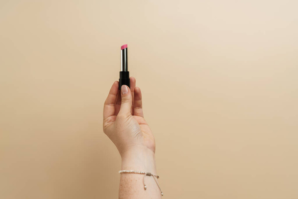 Woman's hand holding lipstick isolated over background - Φωτογραφία, εικόνα