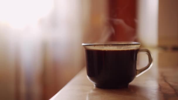 Een kopje warme aromatische koffie staat op tafel. Goedemorgen ontbijt. Verdamping door warme drank. - Video