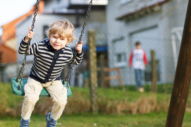 Adorable niño pequeño teniendo divertido swing cadena en playgroun al aire libre
 - Foto, imagen