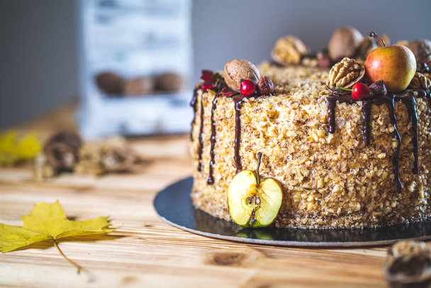 Süßer hausgemachter Nusskuchen mit Schokoladenbelag und Walnüssen und Apfel auf hölzernem Herbsttisch Leckeres ungesundes Dessert - Foto, Bild