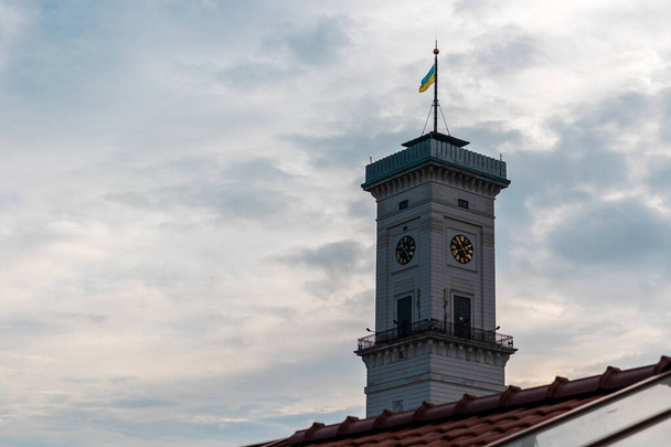 Torre con la bandera de Ucrania y el reloj del Ayuntamiento de Lviv. Hermosa arquitectura antigua en Rynok Square. Lugar muy popular entre los turistas. Calles y arquitectura de la ciudad vieja. Ucrania. - Foto, imagen