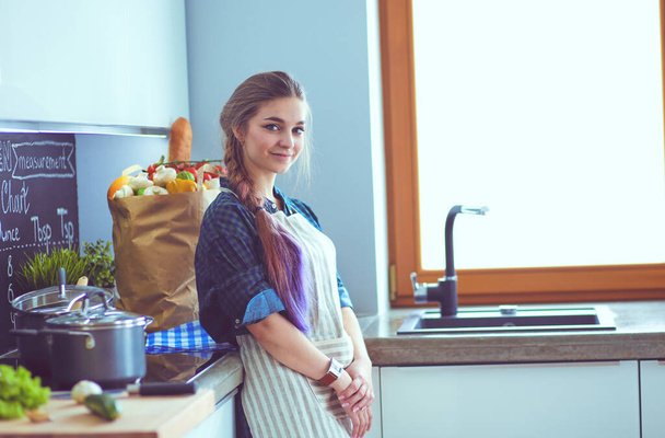 Young woman standing by the stove in the kitchen . - Photo, image