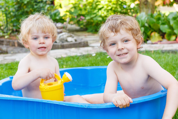 Two sibling boys having fun with water in summer - Foto, immagini
