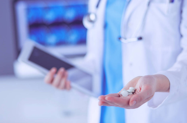 Close-up shot of doctors hands holding pills and tablet at clinic. - Fotó, kép