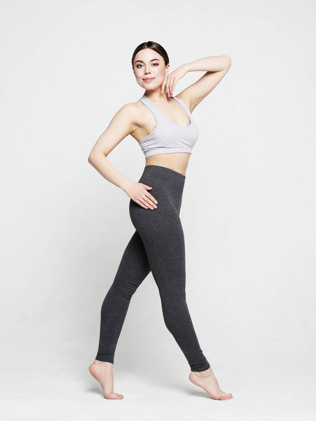 Portrait of beautiful young woman wearing sportswear working out in studio. Fit sporty girl doing yoga. Full length. - Foto, Imagem