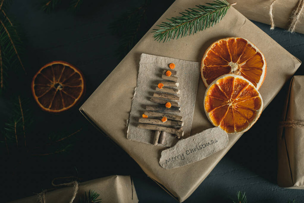 Joulu- ja nollajätteet, ympäristöystävälliset pakkauslahjat voimapaperissa, kuivatut appelsiinit, joulukuusen oksat. ekologinen joululoma käsitteitä, ekologinen sisustus. Laadukas kuva - Valokuva, kuva