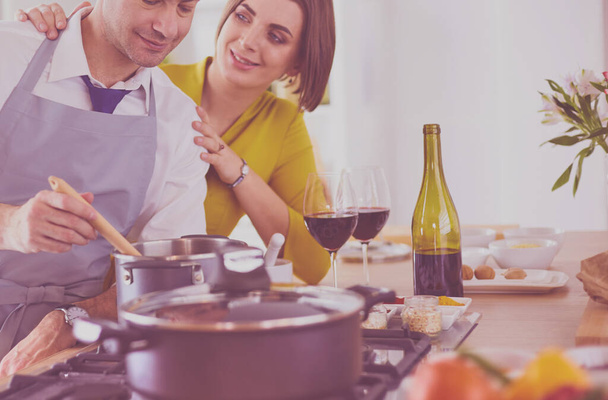 Attractive couple in love cooking and opens the wine in the kitchen while they cook dinner for a romantic evening - Zdjęcie, obraz