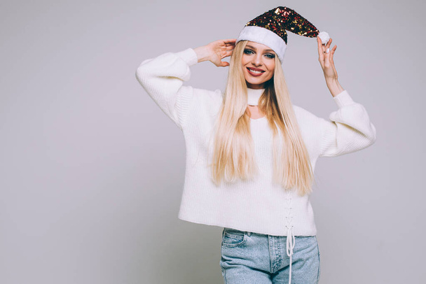 Jovial pretty blonde Caucasian girl in Santa hat. - Foto, Bild