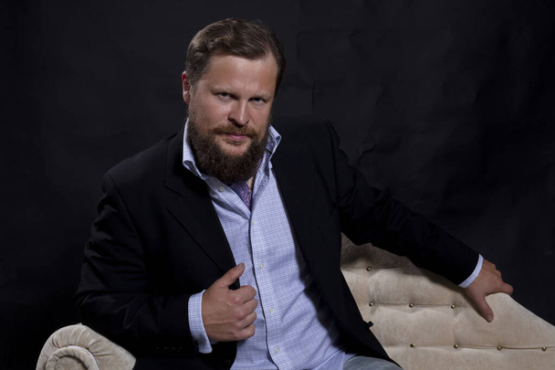 Thoughtful solid bearded man dressed in suit sitting on sofa - Valokuva, kuva