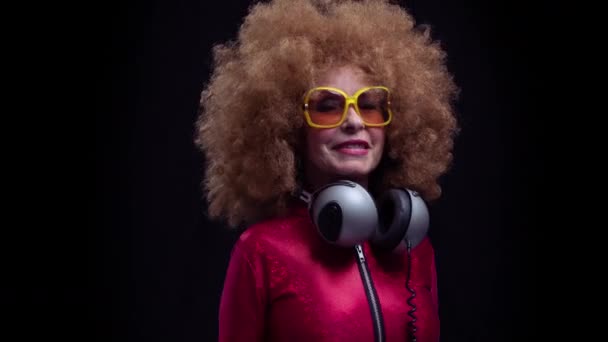 Senior woman dancing in disco with headphones - Záběry, video