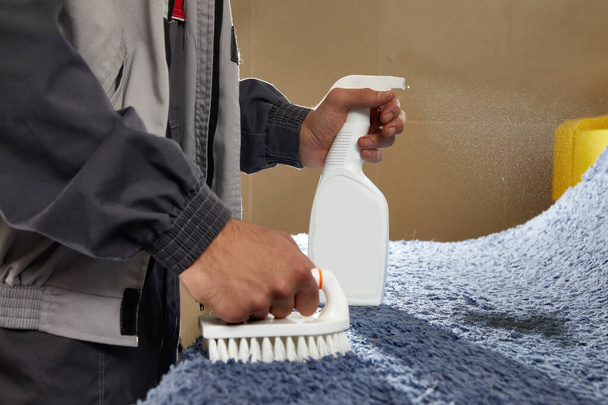 Чоловік Обприскувач для розпилення на сірому килимі для видалення плям у професійній службі прибирання
  - Фото, зображення