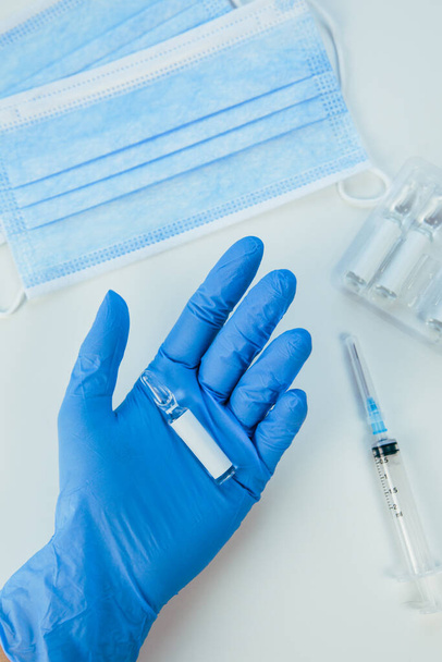 hand in medische handschoenen ampul met vaccin van dichtbij - Foto, afbeelding