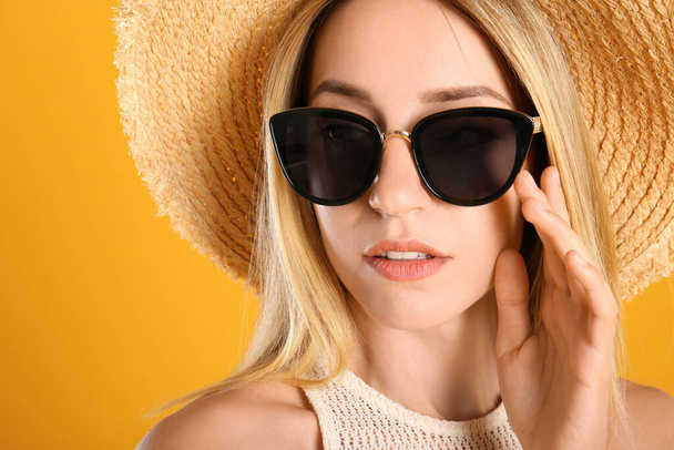 Beautiful woman in stylish sunglasses on yellow background, closeup - Photo, Image