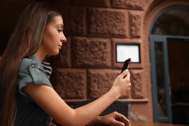 Mladá žena odemyká smartphone s obličejovým skenerem ve venkovní kavárně. Biometrické ověření - Fotografie, Obrázek